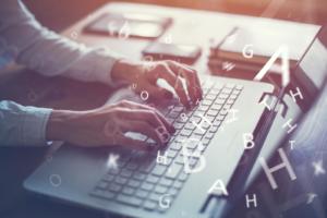 blogging concept - woman's hands typing on laptop with letters overlaid on the image